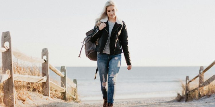 Stylish woman in leather jacket walking by the ocean in Ocean City, NJ.