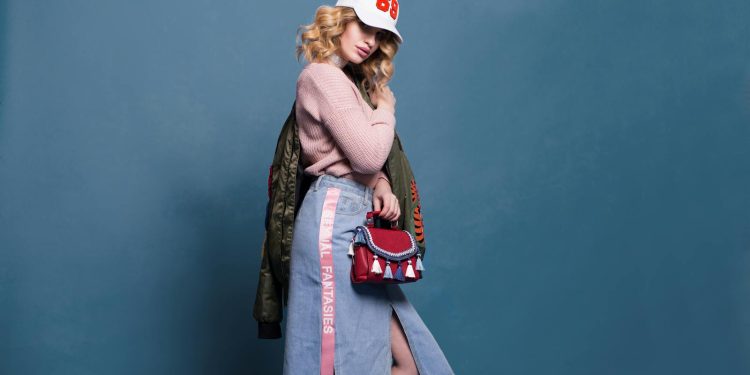 Trendy fashion model poses in a stylish studio setting, showcasing a chic outfit with accessories.