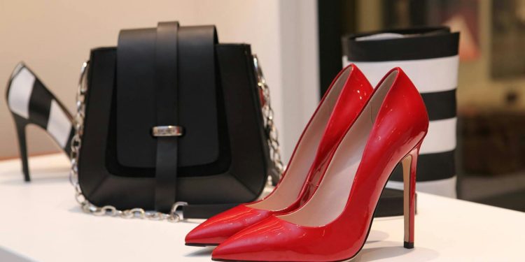 Showcasing sleek red stilettos and a chic black handbag in a luxury boutique setting.