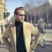 Stylish man in glasses and coat posing outdoors on an urban street in Budapest.